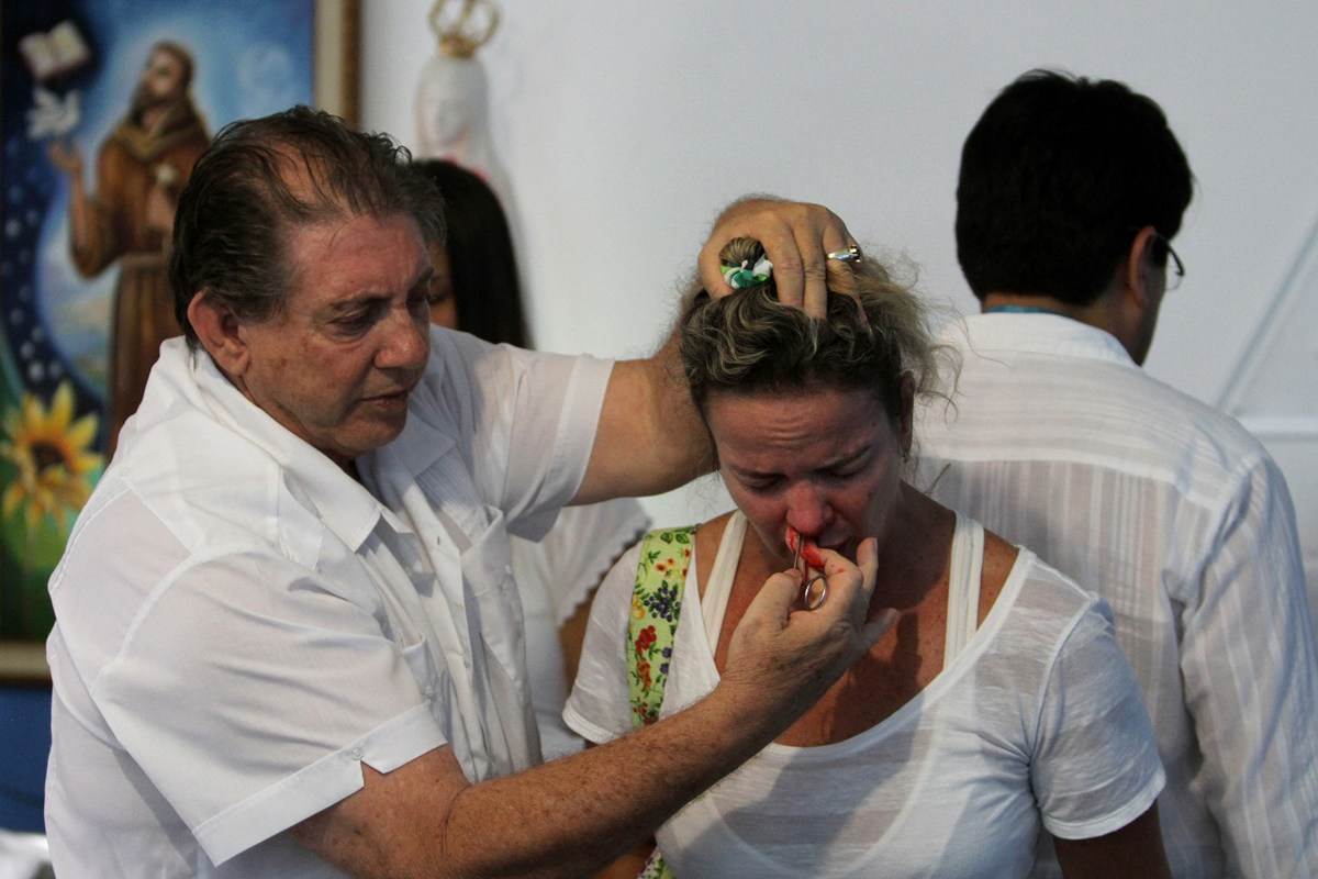 Para cirurgias sem corte, o paciente recebe o passe e segue para a meditação. Com corte, João de Deus pega uma faca de cozinha para a raspagem do olho e uma agulha ou pinça com algodão cheio de água fluidificada – abençoada – para introduzi-la pela fossa nasal (Foto: Reprodução)